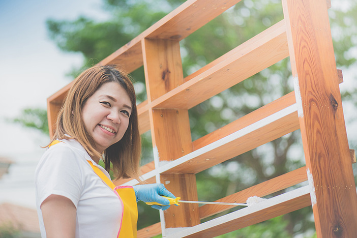 27 Interior & Exterior Preventative Maintenance Tasks for Rentals Asian girl paiting wooden shelf by roller outdoors