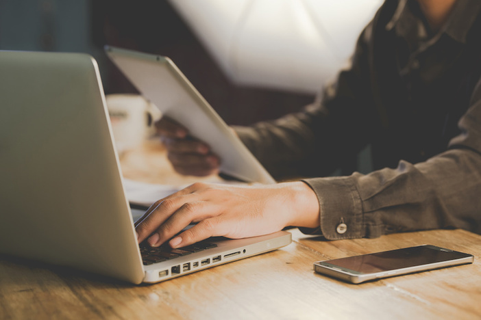 The Hard Question Newbie Wholesalers Should Be Asking Before Jumping In Businessman working at office desk and signing a document, computers and paperwork all around, t