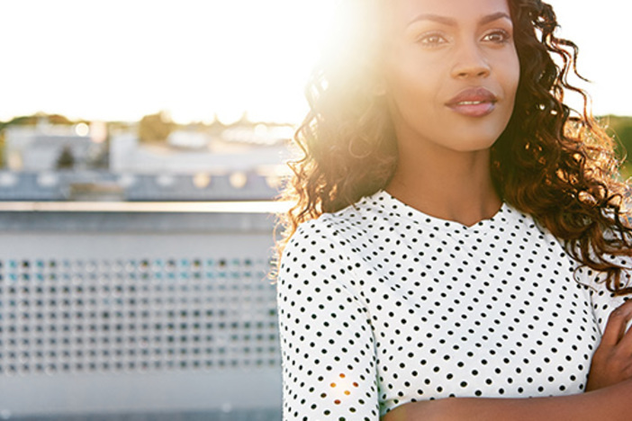 What’s the Yield Curve and How Can It Help You Recession-Proof Your Investments? Confident young woman standing on an urban rooftop daydreaming with her arms folded backlit by the bright flare of the rising sun
