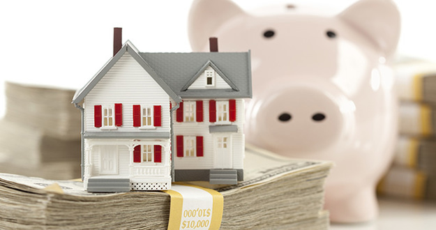 How to Use a HELOC to Buy Real Estate Small House and Piggy Bank with Stacks of Hundred Dollar Bills Isolated on a White Background