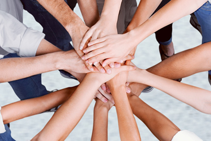 Do This BEFORE You Start Investing in Real Estate closeup of hands piled on top of one another indicating teamwork