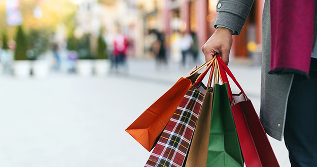4 Key Considerations to Successfully Manage Commercial Property Man holding colorful shopping bags with blurred outdoor mall in background