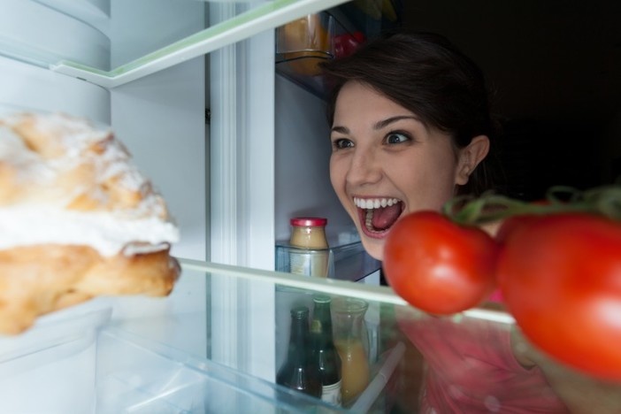 5 Pitfalls of Renting by the Room (& How to Solve Them) woman looking in refrigerator with menacing grin at dessert