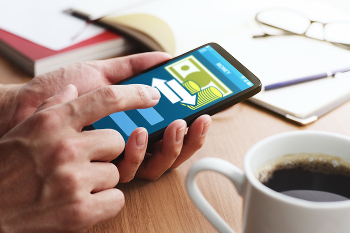 Fact or Fiction: Save on Taxes by Paying Your Own LLC a Property Management Fee Using smartphone for money transfer and banking. Closeup of male touching smartphone screen for using app at table.
