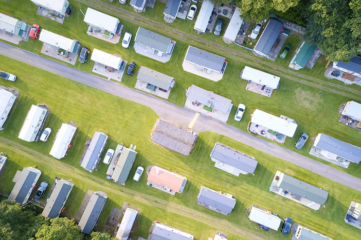 8 Impressive Benefits of Mobile Home Park Investing Caravan site park aerial view illuminated by summer sun