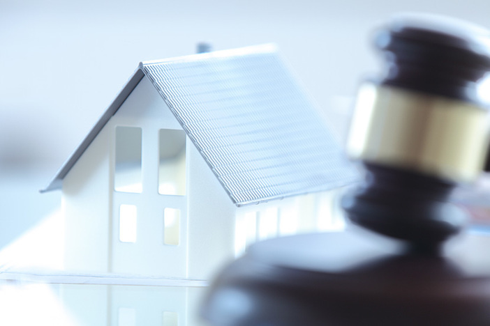 The 5 Biggest Risks of Buying Foreclosures at Auction Close up Conceptual White Miniature House on Top of the Table Beside Court Gavel.