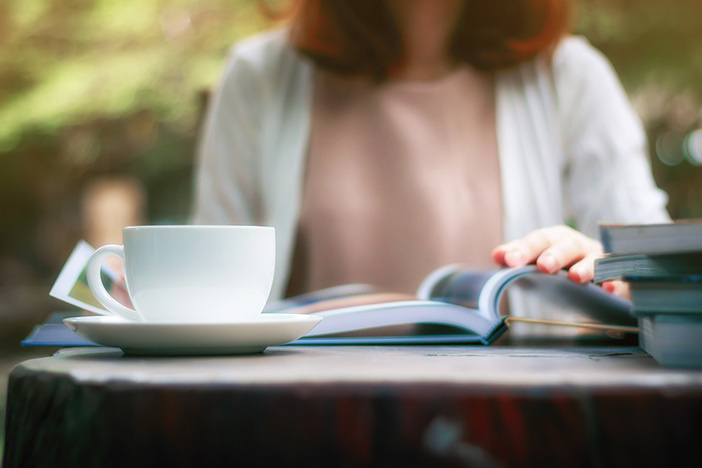 Recession Survival: Everything You Need to Know Is in These Books Close up of woman reading a book and drinking coffee in the garden.