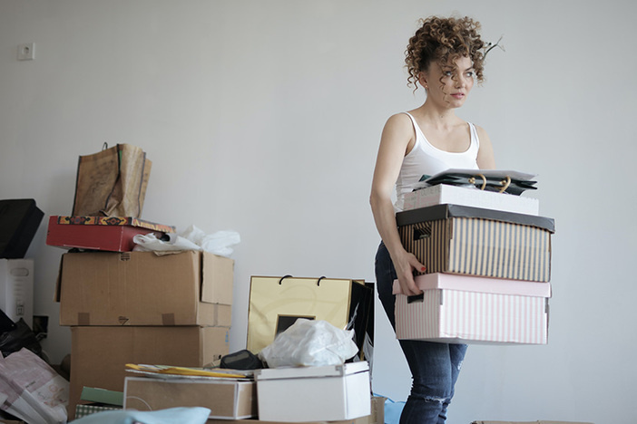 woman carrying stack of boxes with more boxes stacked in background