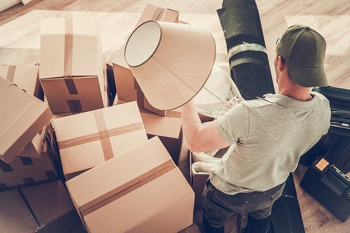 Advantages of 18-Hour Cities for Real Estate Investors in 2020 (& Beyond) Caucasian Divorced Men in His 30s Moving Out From His Home. Staying Between Cardboard Boxes Preparing to Pack His Lamp.