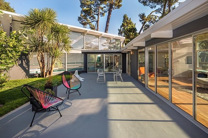 Which Era’s Homes Are Most Valuable? Modern home with large glass sliding doors and outdoor furniture