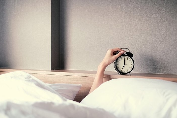 The No. 1 Thing You Can Do To Improve Everything in Your Life (Bonus: It’s Ridiculously Easy!) Woman sleep on the bed turns off the alarm clock wake up at the morning
