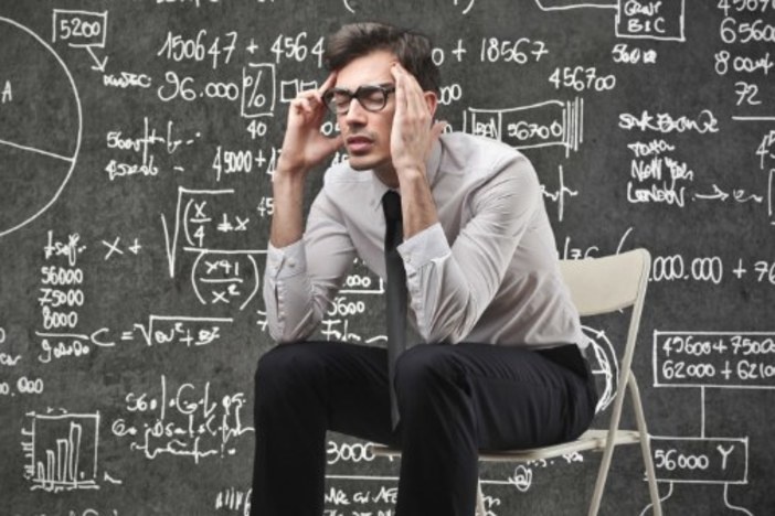 Finding the Right Deal: Why the Numbers Aren’t as Universally Conclusive as You Think man sitting clutching temples in front of blackboard filled with calculations