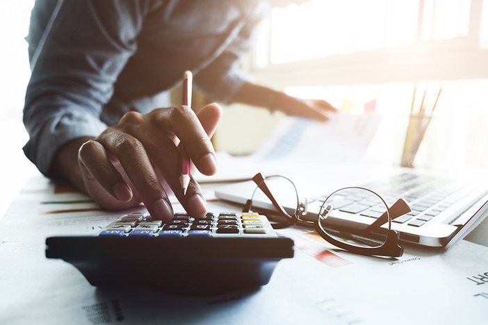 Does a 401(k) Make Sense, or Should I Invest Those Funds Elsewhere? Close up of businessman or accountant hand holding pen working on calculator to calculate business data, accountancy document and laptop computer at office, business concept