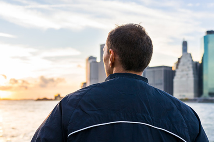 10 Challenges to Seriously Consider BEFORE Quitting Your Day Job man looking out over river at cityscape and sunset
