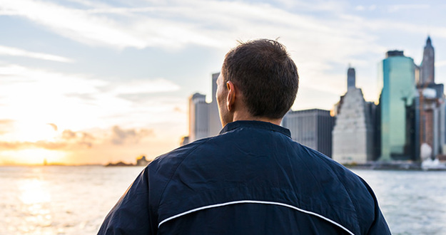 10 Challenges to Seriously Consider BEFORE Quitting Your Day Job man looking out over river at cityscape and sunset