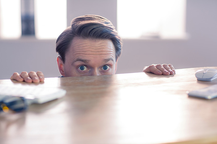 The 7-Step Antidote to Cure the Silent Wealth-Killer Known as Analysis Paralysis Nervous businessman peeking over desks