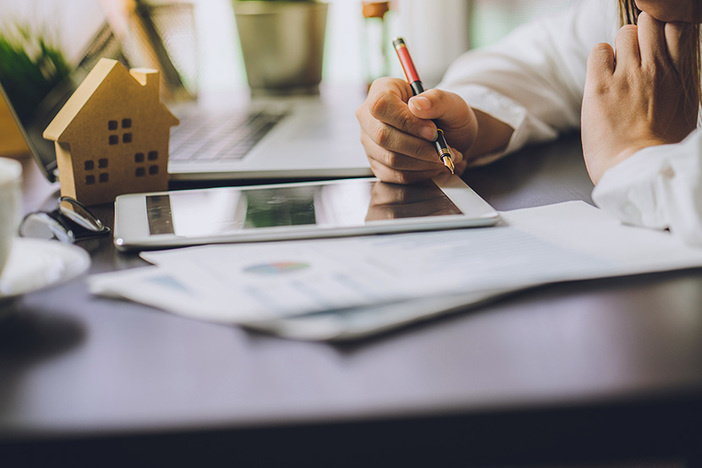 The Irrefutable Advantage Real Estate Investors Have Over Stock Investors Hand of Business people calculating interest, taxes and profits to invest in real estate and home buying